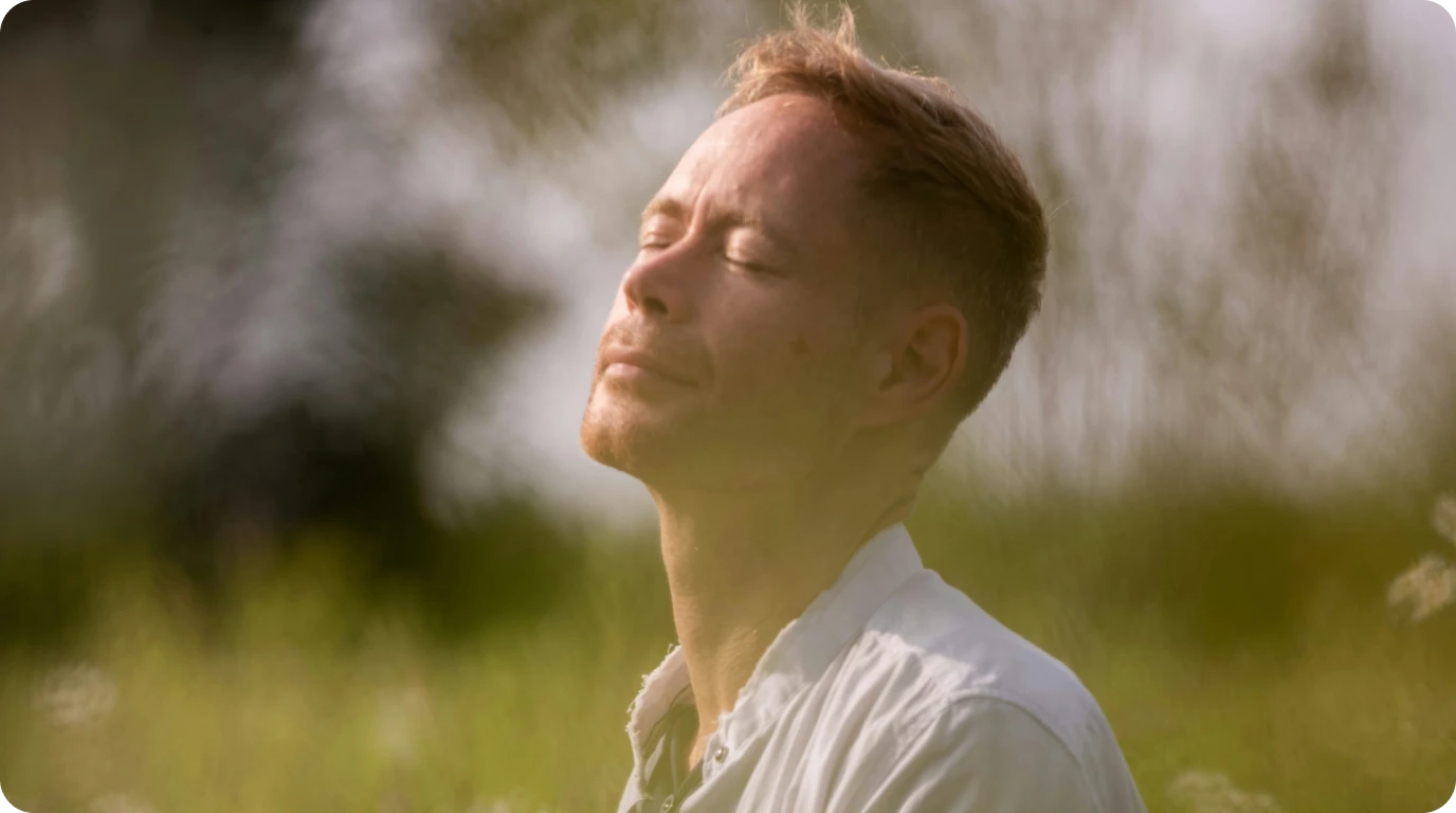 man with closed eyes in a field with head tilted towards the sky