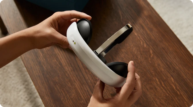 Person holding Flow headset on a wooden surface