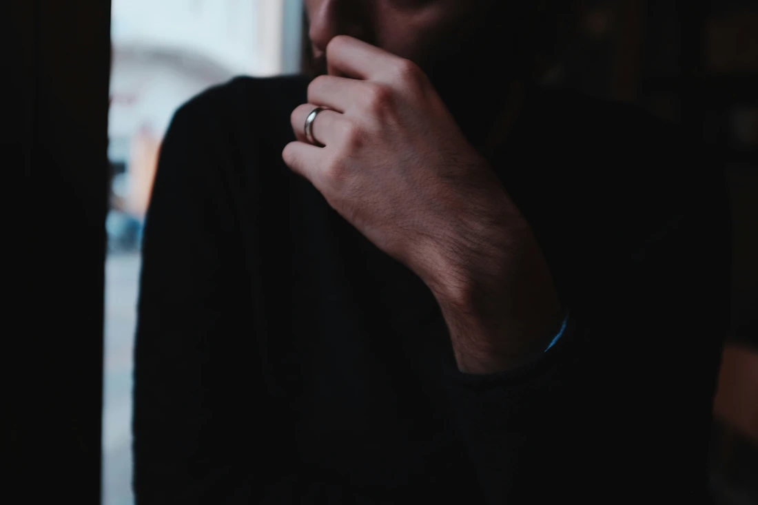 man raising is left hand and weddings ring on his finger